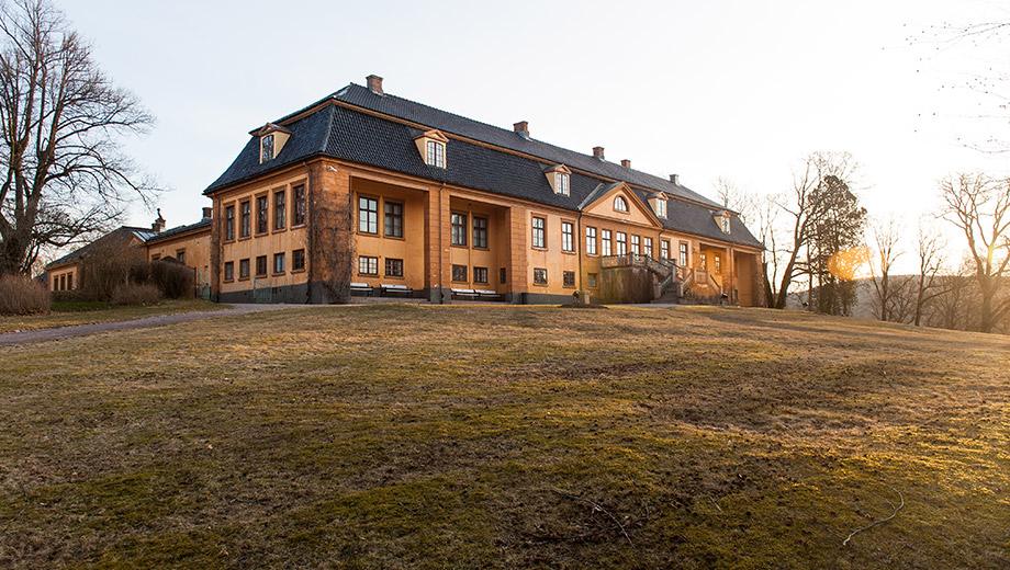 Hovedbygningen på Bogstad gård i varm oker, med valmet tak