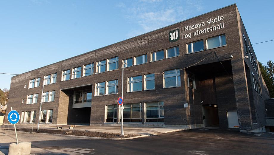 Skole og idrettshall i mørk tegl med store vindusbånd