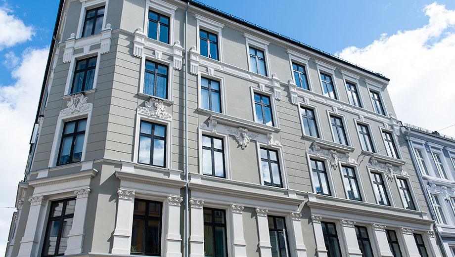 Lys bygård i fem etasjer med rik stukkatur rundt vinduene